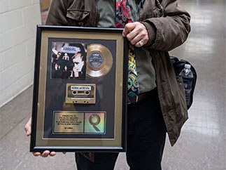 A framed platinum record award held up for the camera